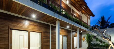Une maison moderne dotée d’une piscine, d’une façade en bois et d’un balcon agrémenté de plantes.