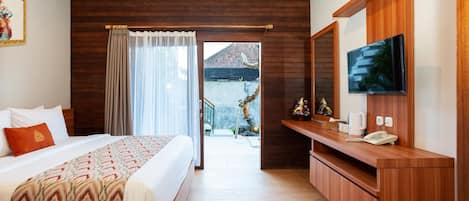 A hotel room with a bed, a TV, a wooden desk, and a balcony with a view.