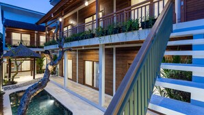 Un immeuble à plusieurs étages doté de balcons en bois, d’une piscine et d’un escalier.