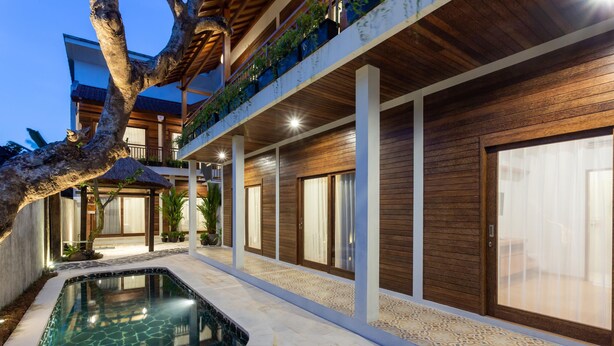Une maison moderne dotée d’une piscine, d’une façade en bois et d’un balcon agrémenté de plantes.
