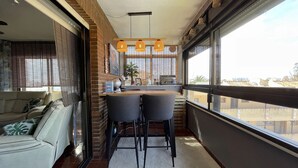 A modern kitchen with a dining area, large windows, and a view of the cityscape.