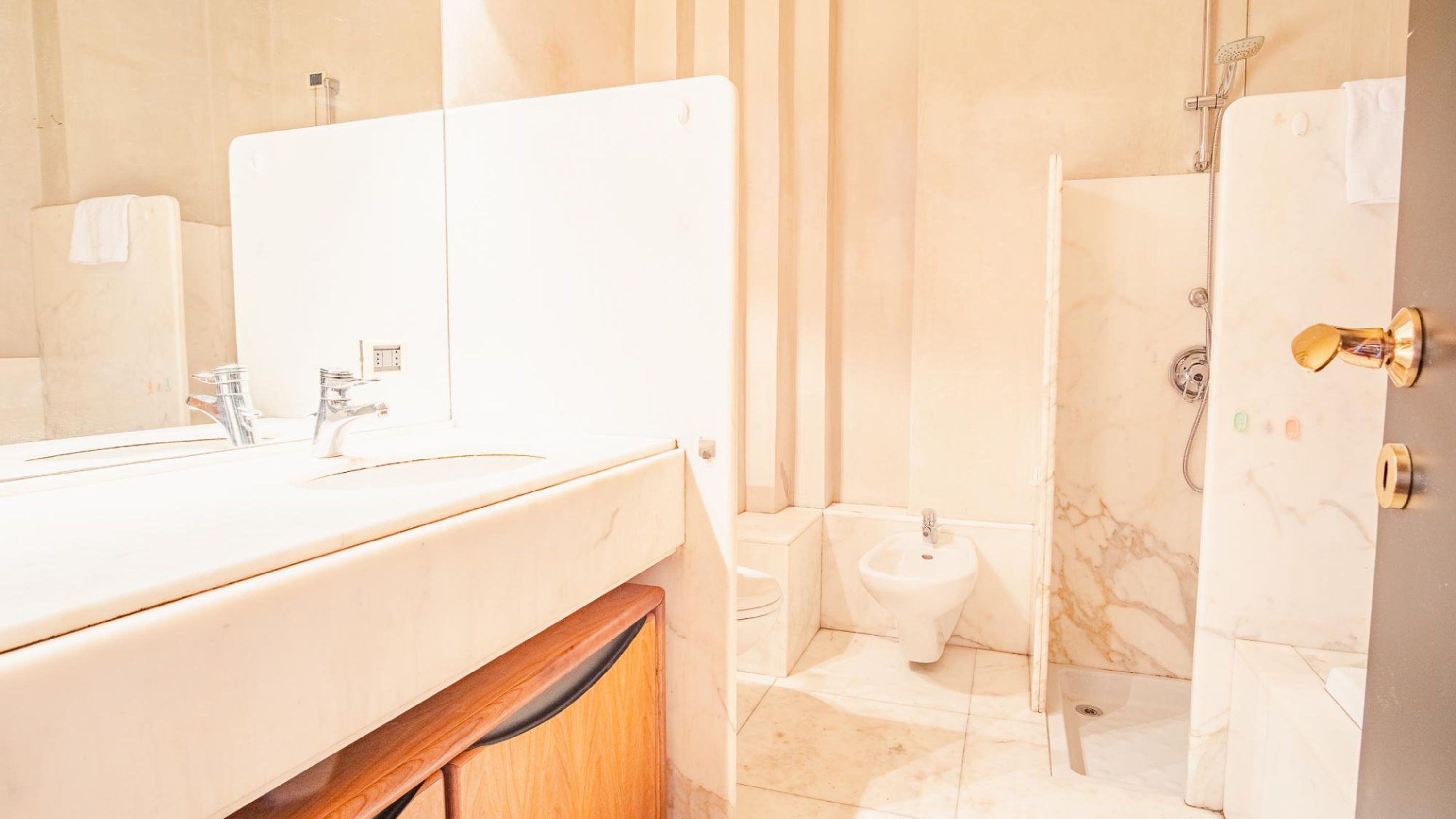 A bathroom with a large mirror, a sink, a toilet, and a shower.