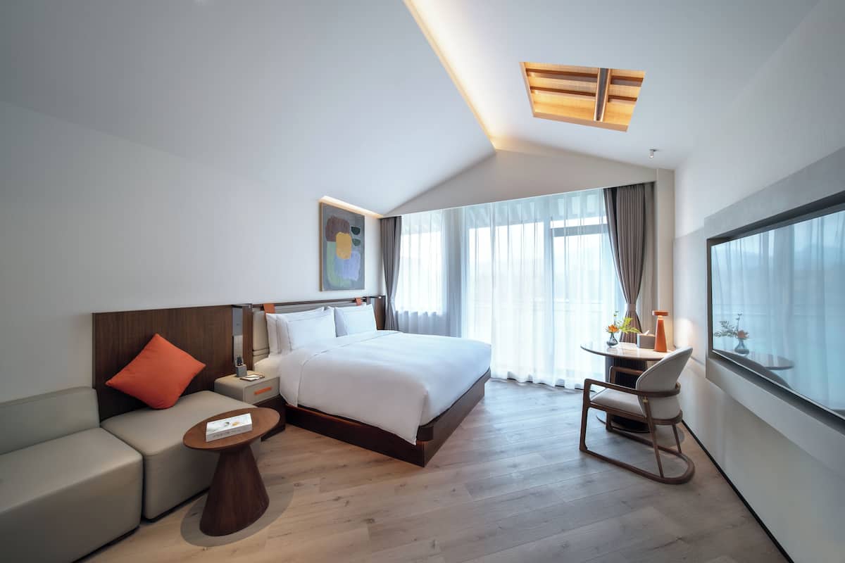 Une chambre d’hôtel moderne, dotée d’un grand lit, d’un canapé, d’un bureau et d’une chaise.