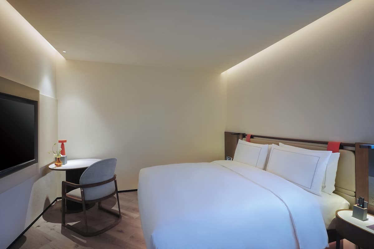 Une chambre d’hôtel avec un grand lit, un bureau et une télévision.