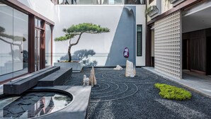 A courtyard with a koi pond, a bonsai tree, and a traditional Japanese building. - TELLUS. Qingchengshan Hot Spring Hotel (Chengdu)