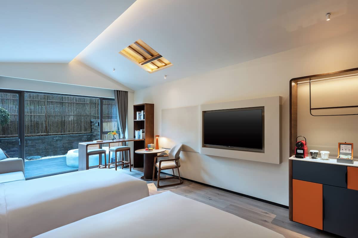 Une chambre d’hôtel moderne dotée d’une grande télévision, de sièges confortables et offrant une vue sur l’extérieur.