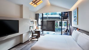 A modern hotel room with a large bed, a flat-screen TV, a small table with a chair, and a balcony with a view of the city. - TELLUS. Qingchengshan Hot Spring Hotel (Chengdu)