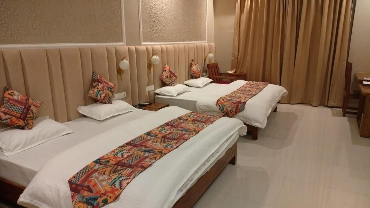 A hotel room with two beds, a wooden headboard, a desk, and a chair.