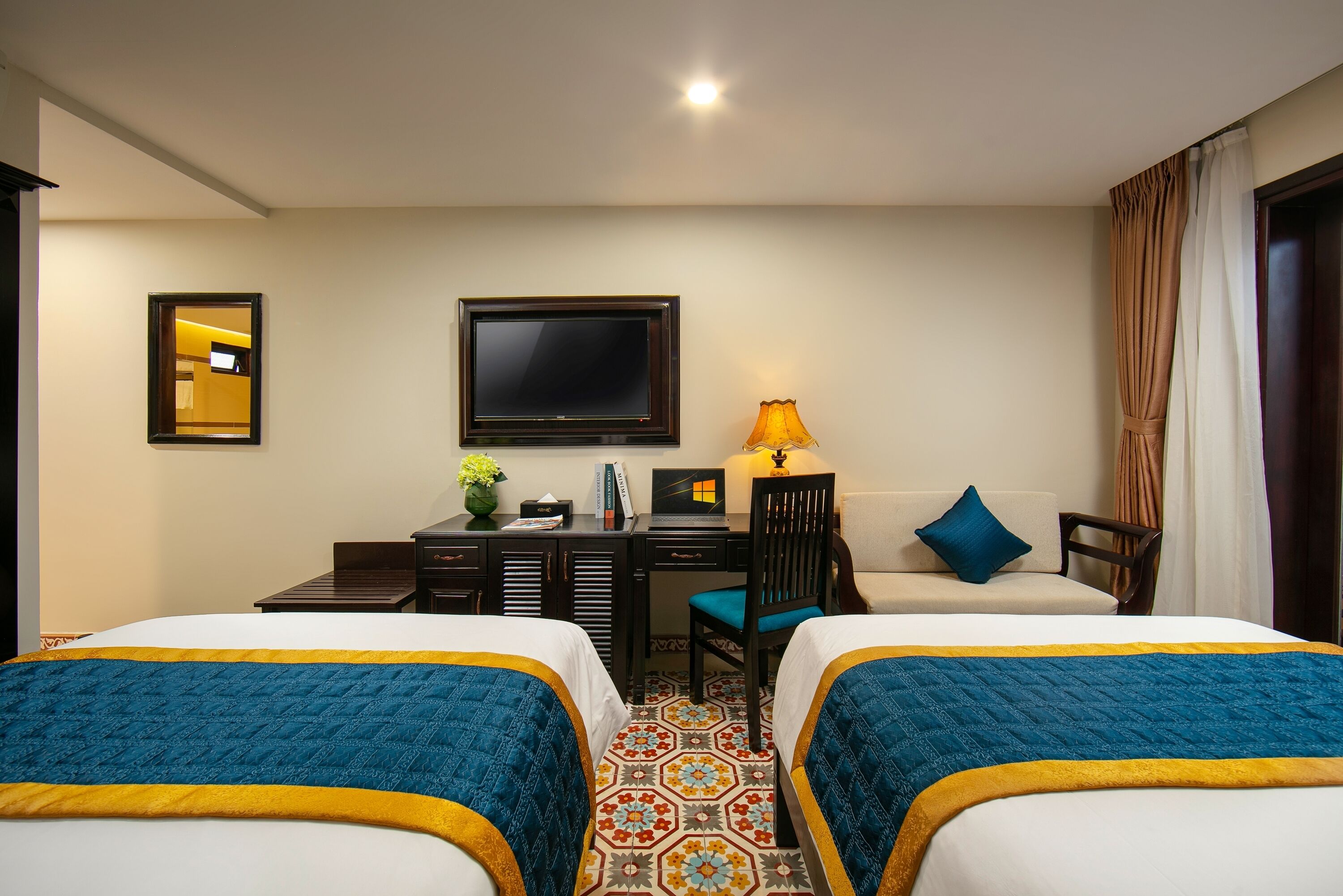 Une chambre d’hôtel avec deux lits, un bureau avec un ordinateur portable, une télévision et une lampe.