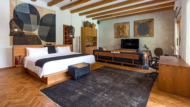 A modern bedroom with a large bed, wooden headboard, a TV, and a desk area. - Cheerful 3BR Villa W/ Pool & Garden, Bali Villa 2213 (Seminyak)