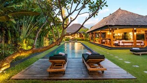 A poolside area with lounge chairs and a thatched-roof structure. - Cheerful 3BR Villa W/ Pool & Garden, Bali Villa 2213 (Seminyak)
