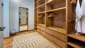 A walk-in closet with wooden shelving, a mirror, and hanging clothes. - Cheerful 3BR Villa W/ Pool & Garden, Bali Villa 2213 (Seminyak)
