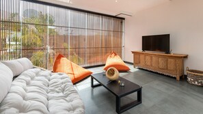 Uma sala de estar moderna com um sofá, uma mesa de centro e uma televisão sobre um armário de madeira.