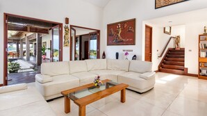 A spacious living room with a white sofa, a glass coffee table, and a painting on the wall. - Airy 7BR Villa With Amazing Hot Tub & Pool, Bali Villa 2234 (Sukawati)
