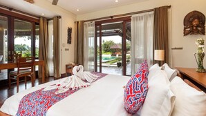 A hotel room with a large bed, a desk, and a view of a swimming pool. - Airy 7BR Villa With Amazing Hot Tub & Pool, Bali Villa 2234 (Sukawati)