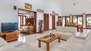 A spacious living room with a flat-screen TV, a sofa, a coffee table, and a dining area with wooden furniture. - Airy 7BR Villa With Amazing Hot Tub & Pool, Bali Villa 2234 (Sukawati)