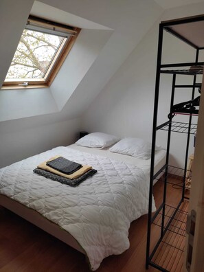 Une chambre avec un plafond en pente, un puits de lumière, un lit superposé et une table de chevet.