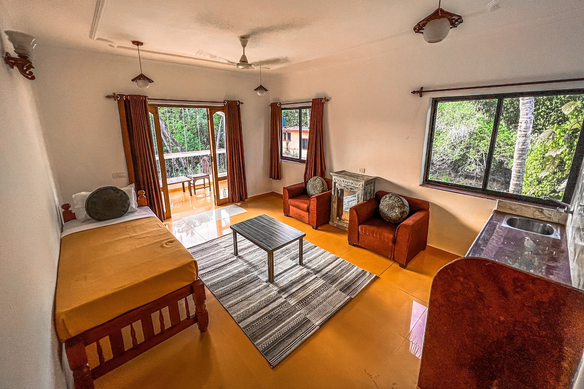 A spacious living room with a wooden coffee table, red sofas, and a view of greenery through large windows.
