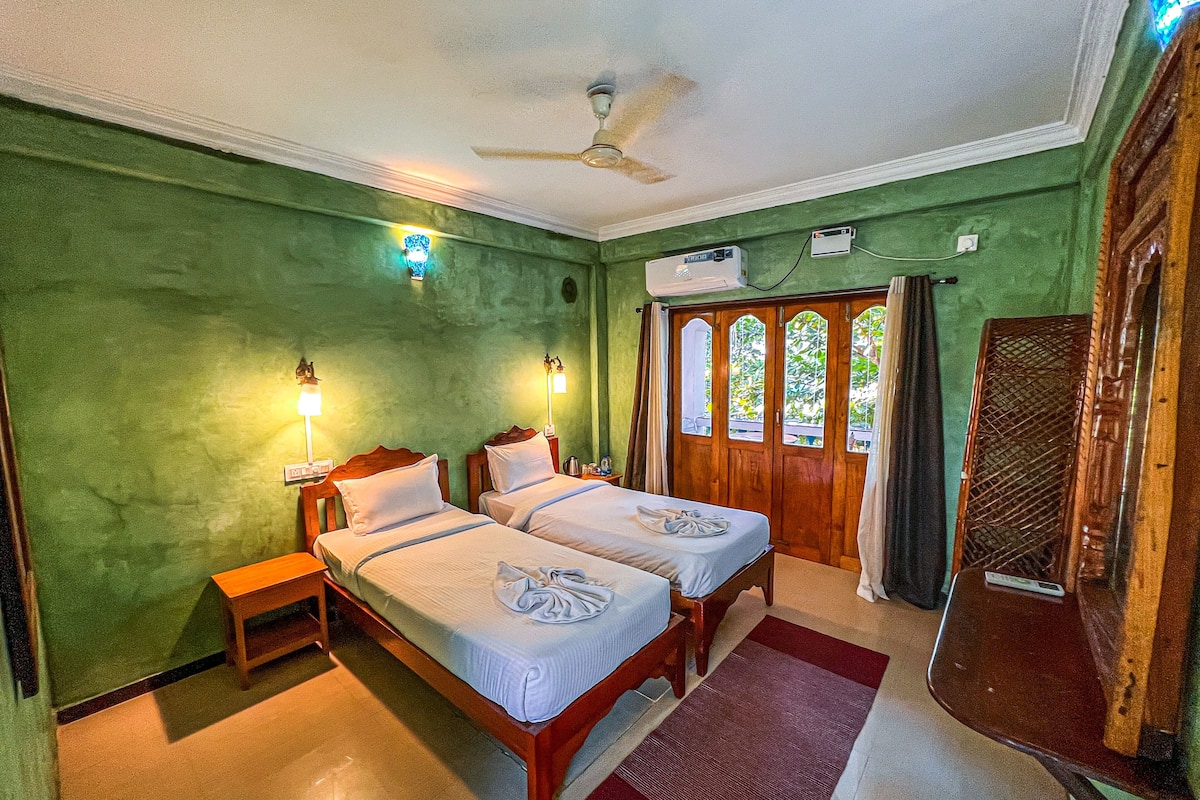 A room with two beds, a ceiling fan, and a window with curtains.
