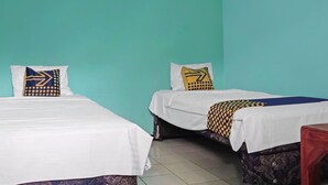 A room with two beds, each with a white bedspread and patterned pillows. The walls are painted teal, and the floor is tiled. - Hotel O Amazon Homestay Syariah 2 (Tjihadak)