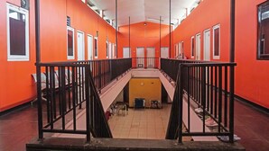 A corridor with orange walls, multiple doors, and a central staircase. - Hotel O Amazon Homestay Syariah 2 (Tjihadak)