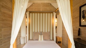 Een slaapkamer met een groot bed, gestreept behang en een hemelbed.