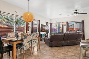 Ein geräumiger Wohnbereich mit Esstisch, Sofa und Deckenventilator.