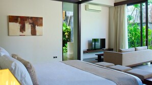 Une chambre d’hôtel moderne équipée d’un lit, d’un canapé, d’une télévision et offrant une vue sur la verdure grâce à de grandes fenêtres.