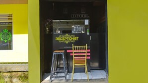 A hotel entrance with a reception desk, a sign reading "KANTOR HOTEL," and a receptionist chair. - Hotel O Cipto Arum (Cilacap)
