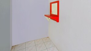 A corner of a room with a white wall and a red-framed mirror mounted on it. - Hotel O Cipto Arum (Cilacap)