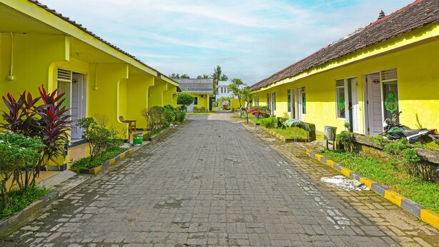 A street lined with yellow buildings, a cobblestone path, and some greenery. - Hotel O Cipto Arum (Cilacap)