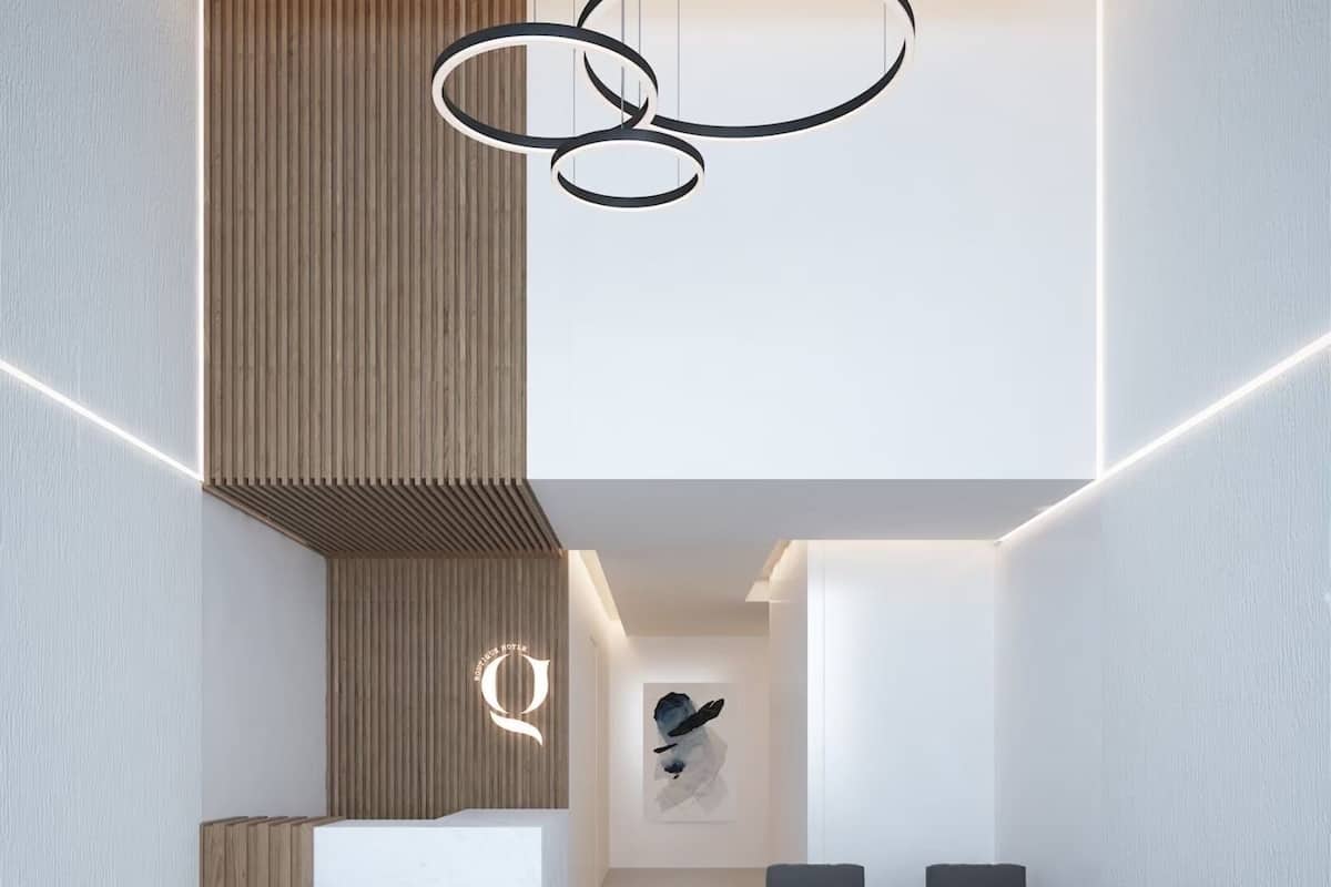Un espace d’accueil moderne avec un mur revêtu de panneaux en bois, un comptoir d’accueil en marbre, une grande œuvre d’art abstraite et une rangée de canapés gris.