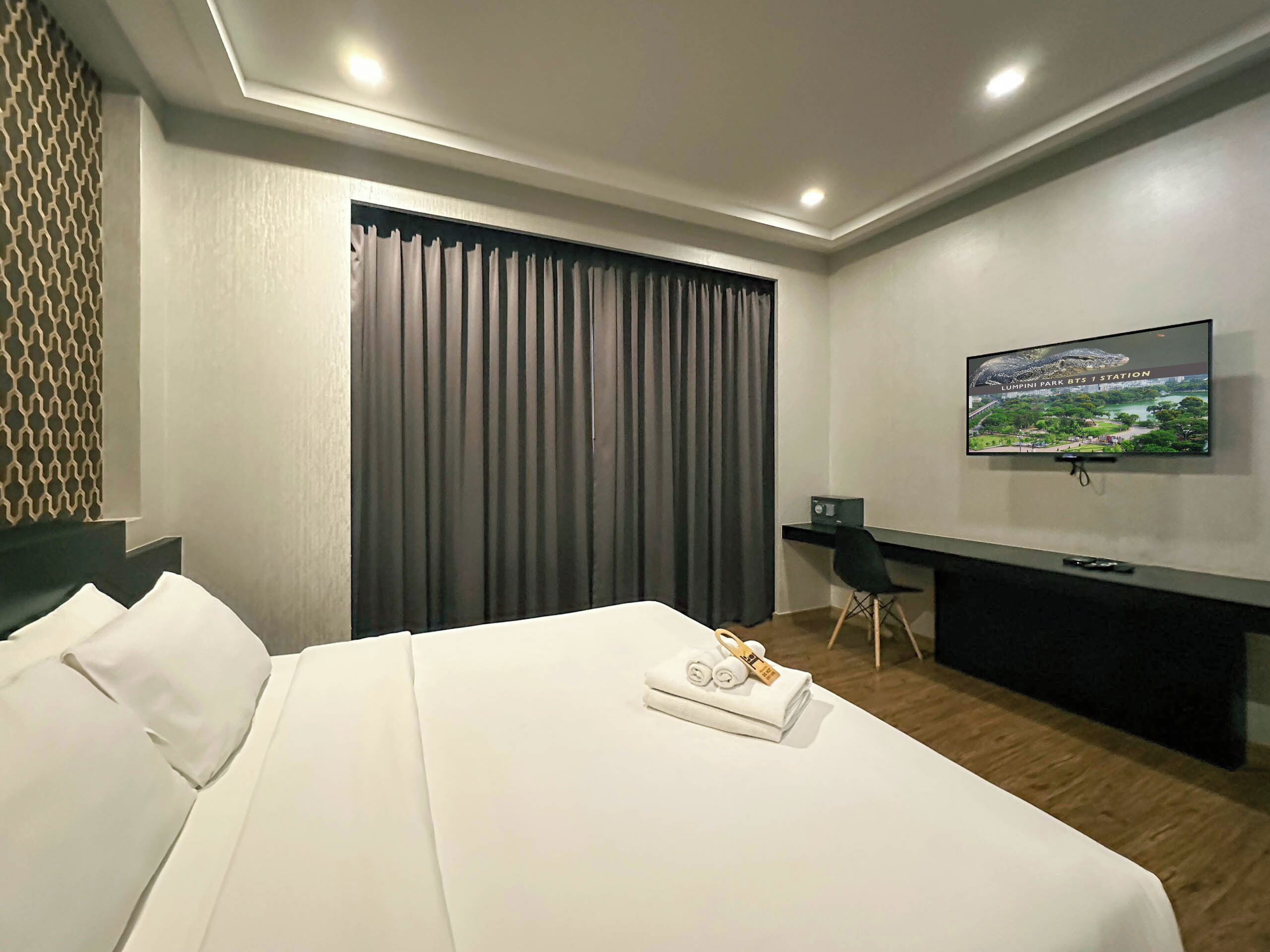 Quarto de hotel com cama, secretária, televisão e vista para um parque.