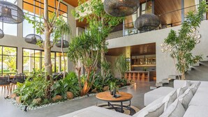 A spacious lobby with a central seating area, a staircase, and a kitchen area visible in the background. - Sea View Pool House (Buleleng)