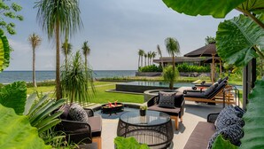 A luxurious outdoor seating area with a pool, lounge chairs, and a view of the ocean. - Sea View Pool House (Buleleng)