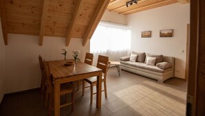 Un coin repas avec une table et des chaises en bois, un canapé et une fenêtre avec des rideaux.