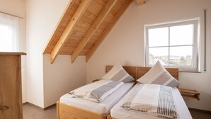 Une chambre à coucher avec deux lits en bois, une fenêtre donnant sur un beau paysage et un plafond en pente.