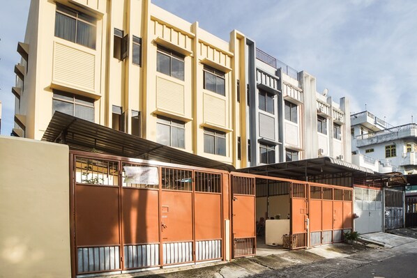 A multi-story residential building with a flat facade, large windows, and a gated entrance.