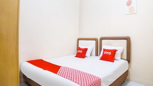 Ein Doppelbett mit zwei roten Kissen, einer roten und weißen Decke und einem hölzernen Kopfteil.
