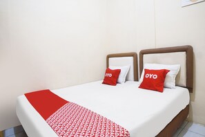 A double bed with a red and white patterned bedspread and two red pillows with the word "OYO" on them.