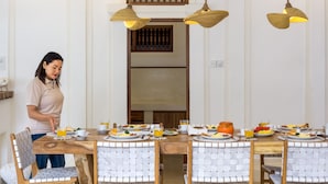 A dining area with a wooden table set for breakfast, including plates of eggs, toast, and fruit. There are three hanging pendant lights above the table. - Wonderful 4BR Villa With Pool, Bali Villa 2212 (Seminyak)