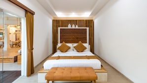 A modern hotel room with a large bed, a wooden headboard, and a small seating area. - Wonderful 4BR Villa With Pool, Bali Villa 2212 (Seminyak)