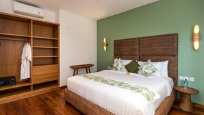 A hotel room with a large wooden wardrobe, a bed with a woven headboard, and a small wooden table. - Modern 4BR Villa W/ Pool & Balcony, Bali Villa 2220 (Kerobokan)