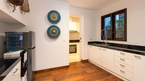 A modern kitchen with white cabinets, a black countertop, and a window with a view of palm trees. - Modern 4BR Villa W/ Pool & Balcony, Bali Villa 2220 (Kerobokan)