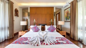 Una habitación de hotel con una cama grande, dos mesitas de noche, un armario y elementos decorativos.