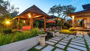 Un jardín cuidado con un mirador, asientos exteriores y un camino de piedra.
