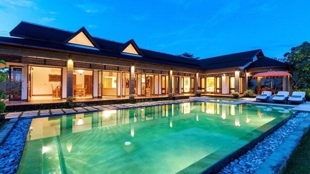 Un moderno resort con una amplia piscina, varias habitaciones de huéspedes y un espacio exterior cubierto.