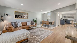 Un salon moderne avec un canapé en cuir marron, une table basse en verre et un tapis à motifs.