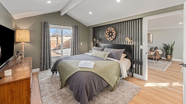 Une chambre à coucher avec un lit, un bureau, une lampe et une vue sur l’extérieur.