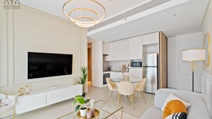 Una sala de estar moderna con un televisor de pantalla plana, un sofá con cojines, una mesa de centro y un comedor con una mesa de vidrio y sillas.